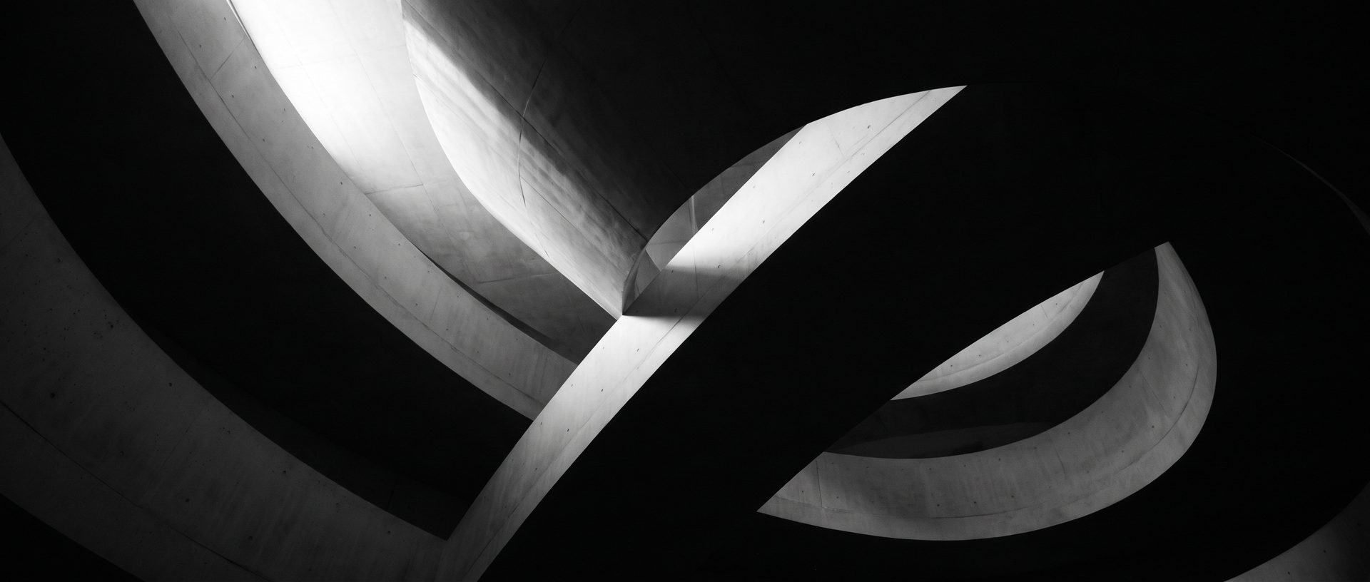 A cavernous vaulted stone interior with flowing curved surfaces, receding into deep shadow.