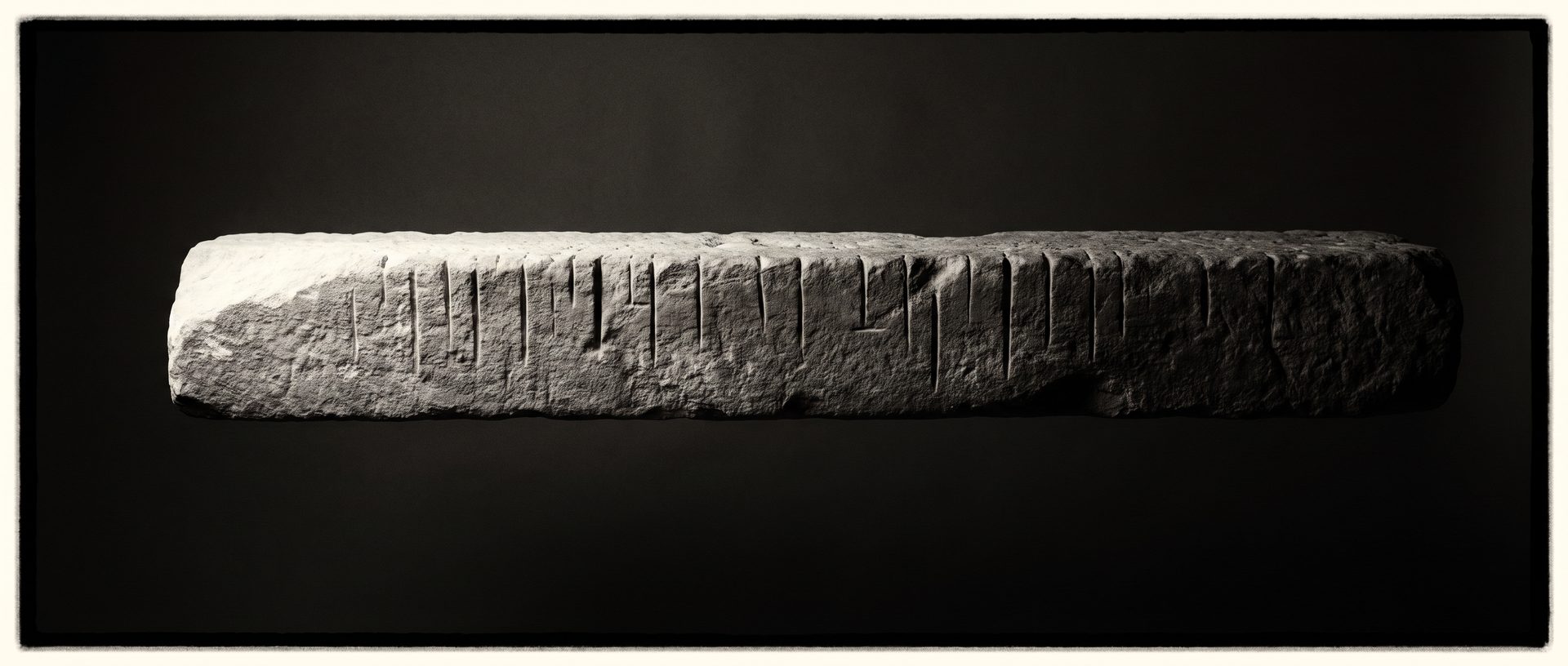 A weathered horizontal stone beam floating in darkness, scored with a series of primitive vertical tally markings.